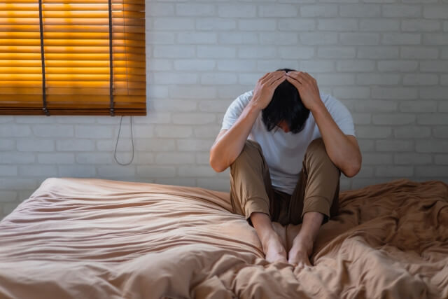 ベッドで頭を抱える男性