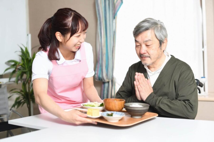 食事をする高齢男性と介護士