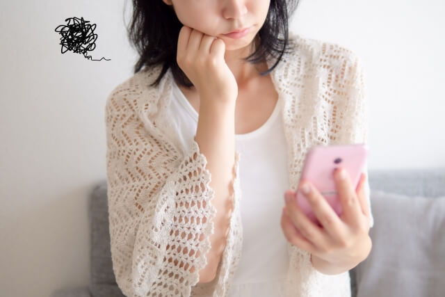 スマホを見ながら悩んでいる女性