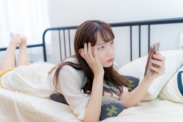 スマホを見て悩んでいる女性
